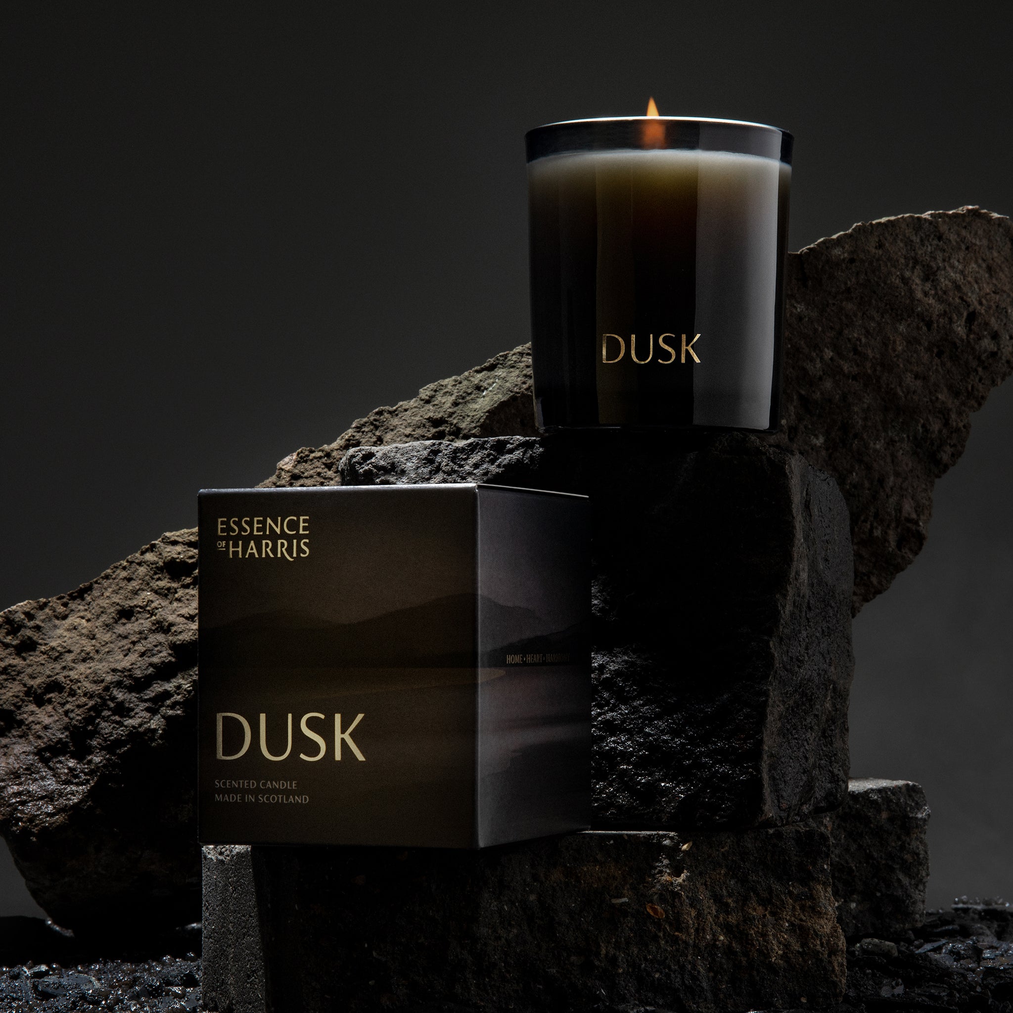 Dusk, wild rhubarb soy wax candle in black smoked glass bottle with gold writing next to sunset illustrated box