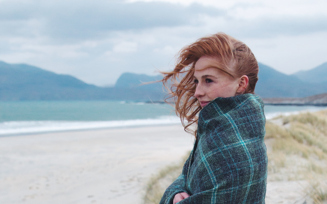 A woman, wrapped in a blanket on a Harris beach
