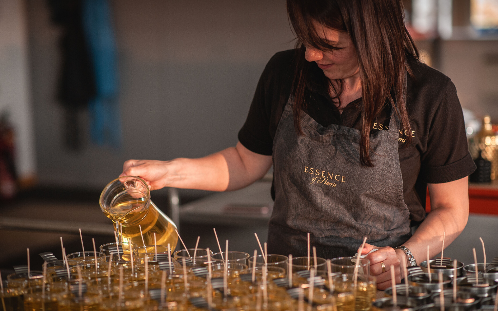 Woman pouring Essence of Harris candles in production