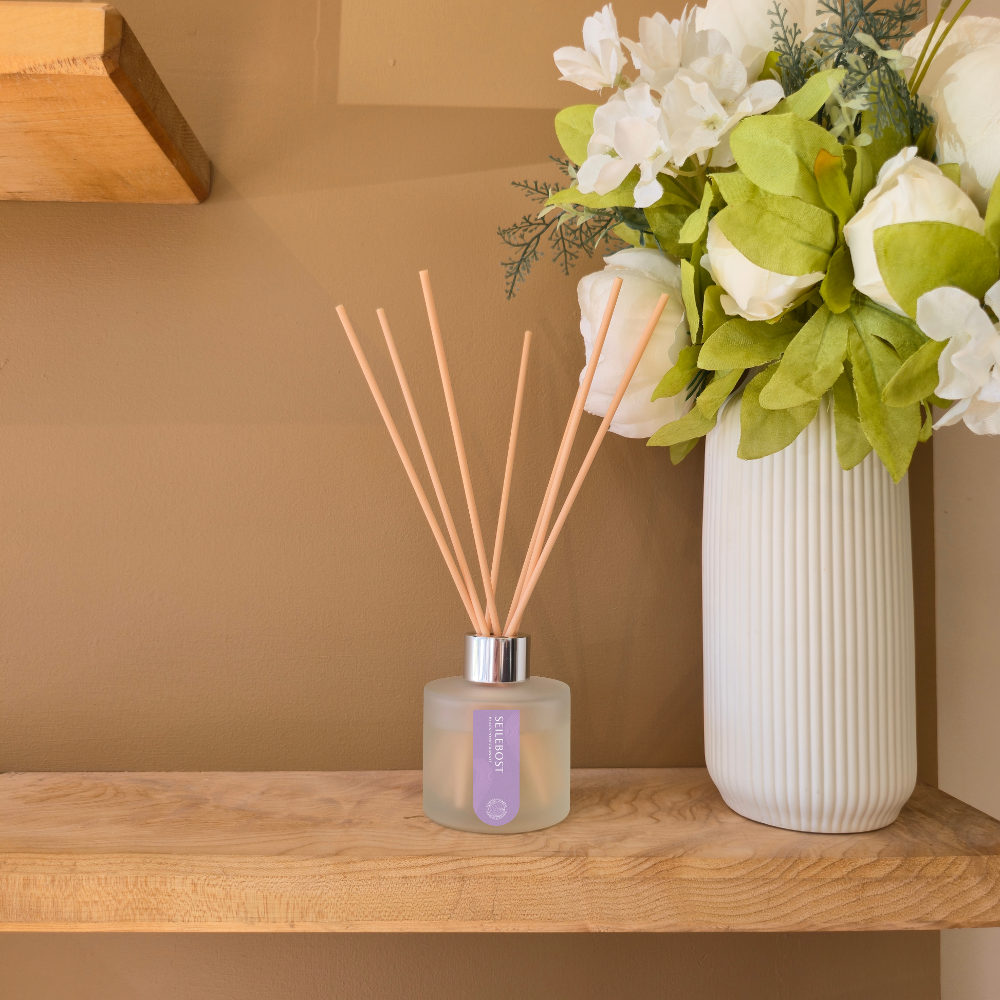 Essence of Harris Seilebost diffuser with reeds on a wooden shelf against a beige wall.