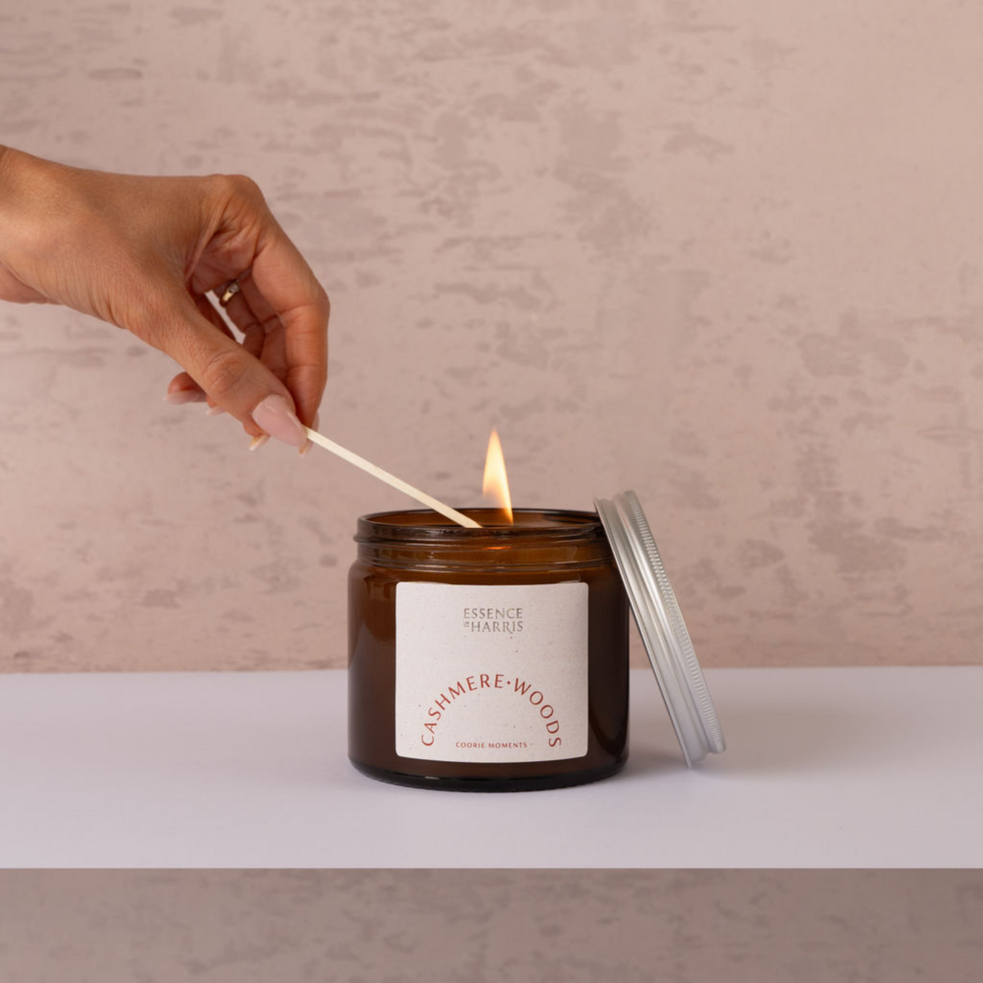 Essence of Harris Cashmere Woods candle in apothecary candle jar, being lit 