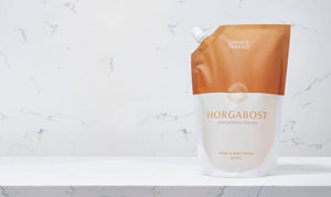 Horgabost, lemongrass and ginger hand and body wash refill in an orange and white pouch on a marble background.