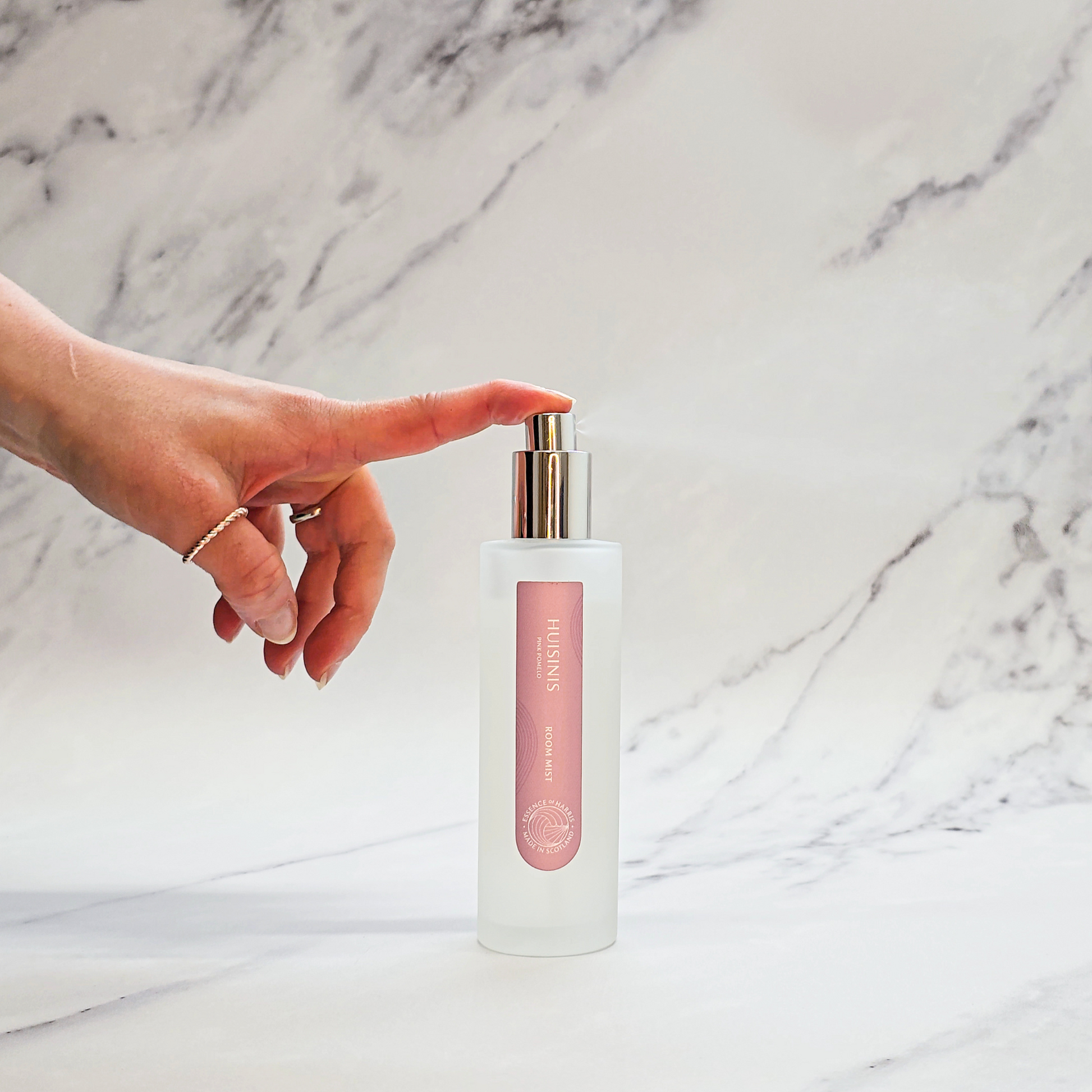 Essence of Harris Huisinis pink pomelo room spray on marble backdrop with hand spritzing spray