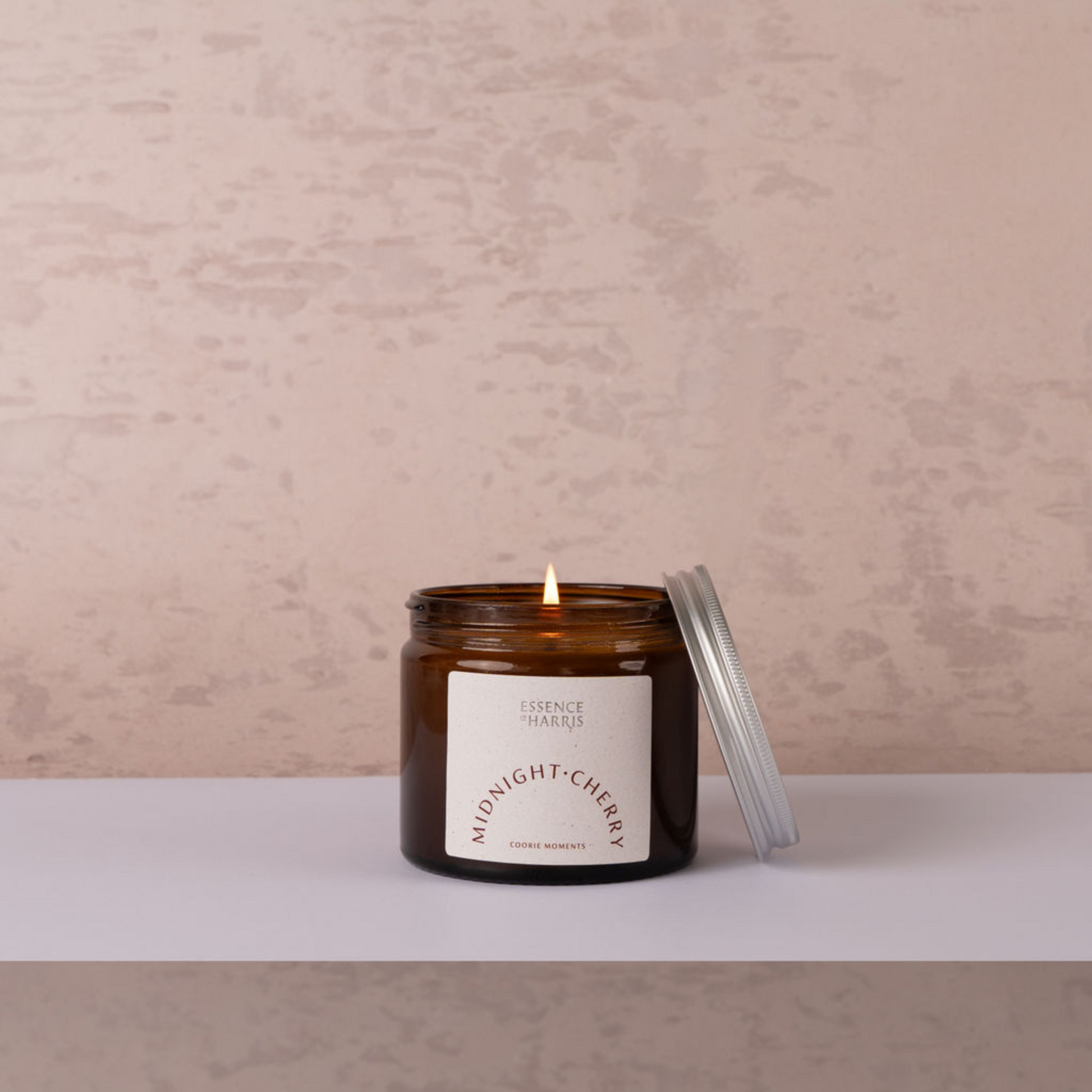 Midnight cherry jar candle, with lit flame on neutral background