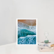 Canvas print depicting a birdseye view of waves and beach with text overlay 'Our Happy Place' in white frame