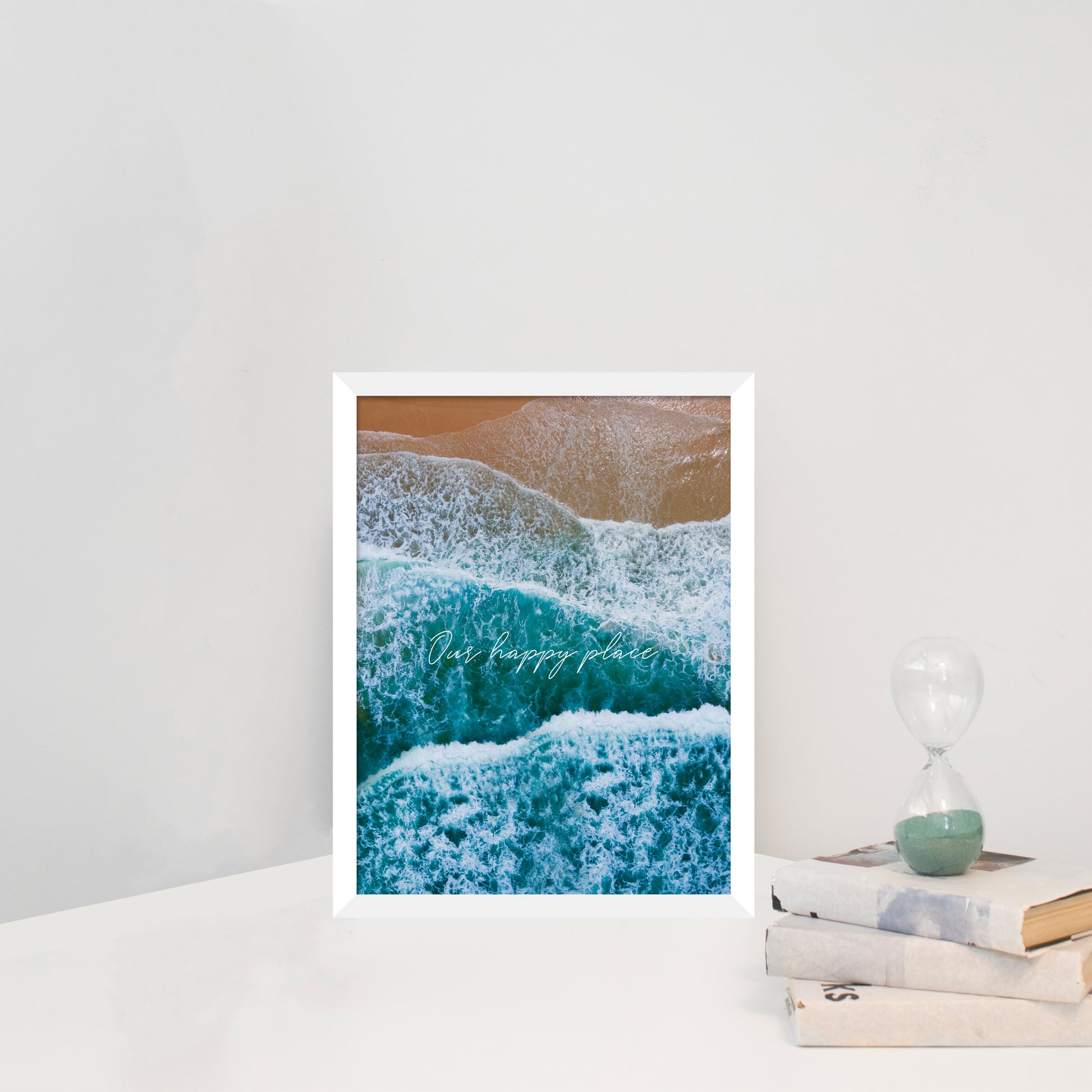 Canvas print depicting a birdseye view of waves and beach with text overlay 'Our Happy Place' in white frame
