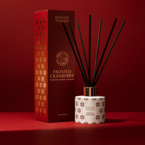 Frosted cranberry Christmas reed diffuser with festive pattern and black reeds next to red box