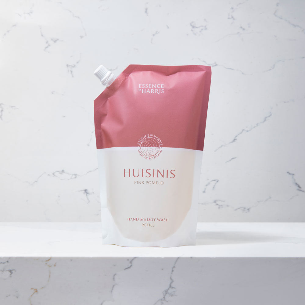 Huisinis, pomelo and grapefruit hand and body wash refill in a pink and white pouch on a marble background.