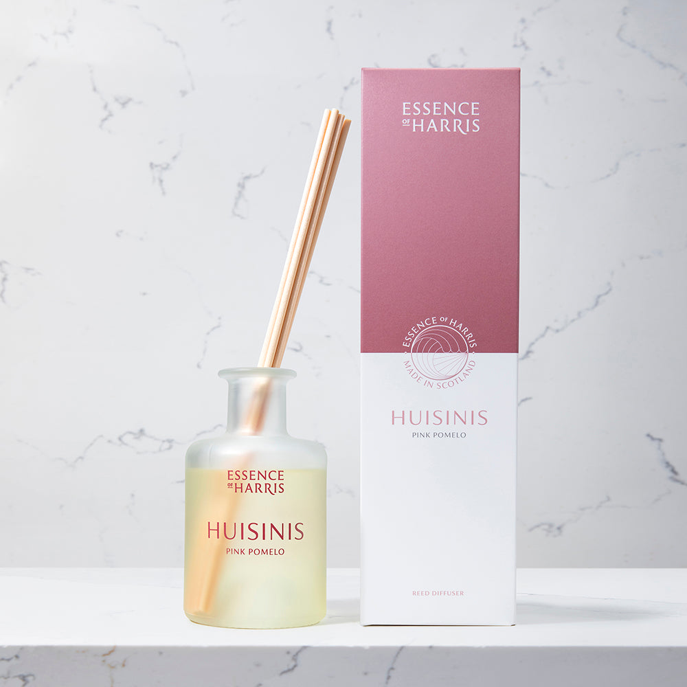 Huisinis, pink pomelo and grapefruit reed diffuser in frosted glass bottle next to pink and white packaging