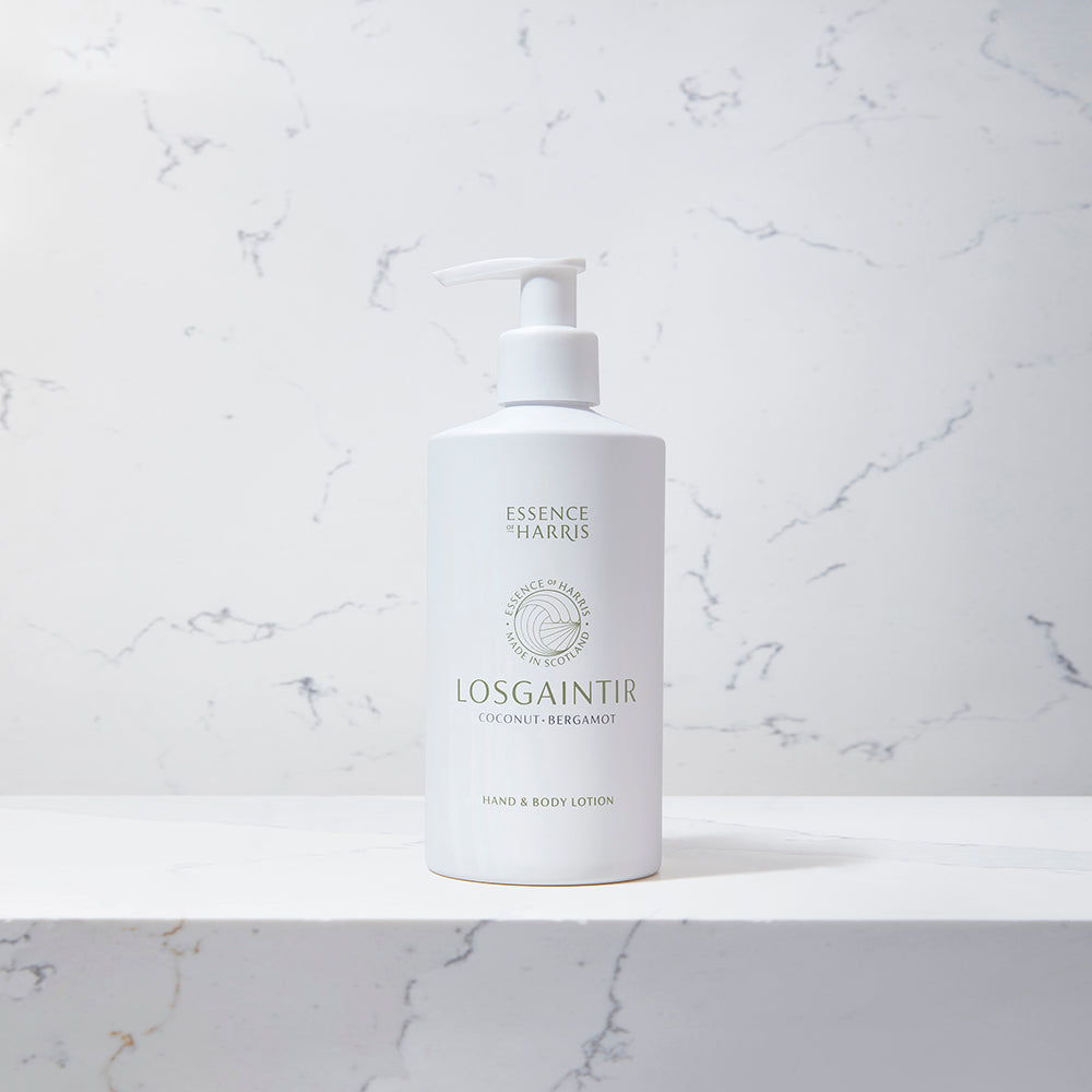 Losgaintir, coconut and bergamot hand and body lotion in a white 300ml pump bottle on a marble background.