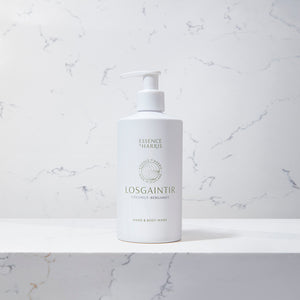 Losgaintir, coconut and bergamot hand and body wash in a white bottle on a marble background.